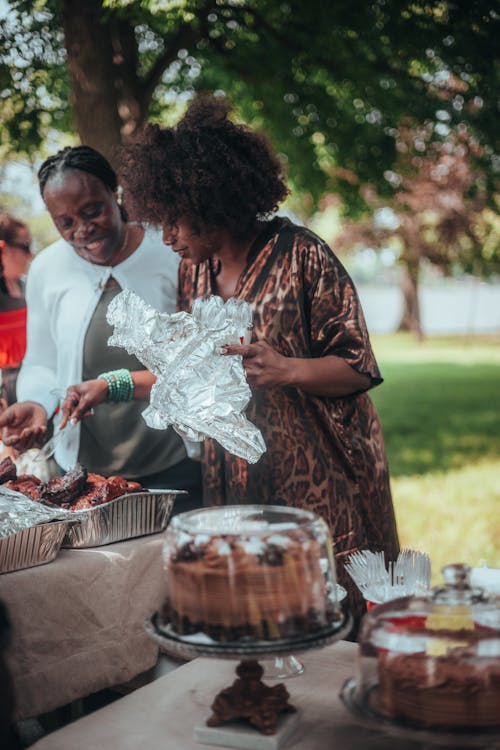 Women Standing behind the Tables with Food in the Garden 