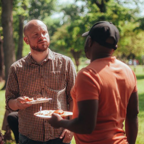 Two people talking over food at an outdoor party — photo by Samuel Peter on Pexels