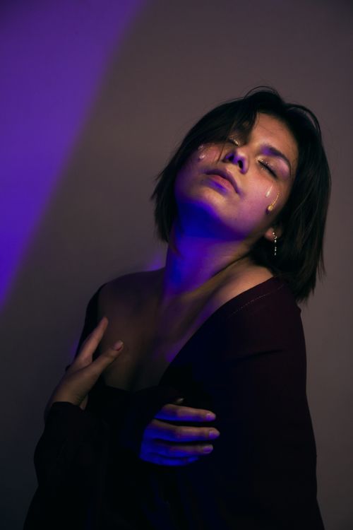 Free Portrait of a woman with closed eyes, emotional pose, and creative lighting effects. Stock Photo