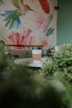 Enjoy a serene morning in a café with a coffee cup on table and vibrant wall art.