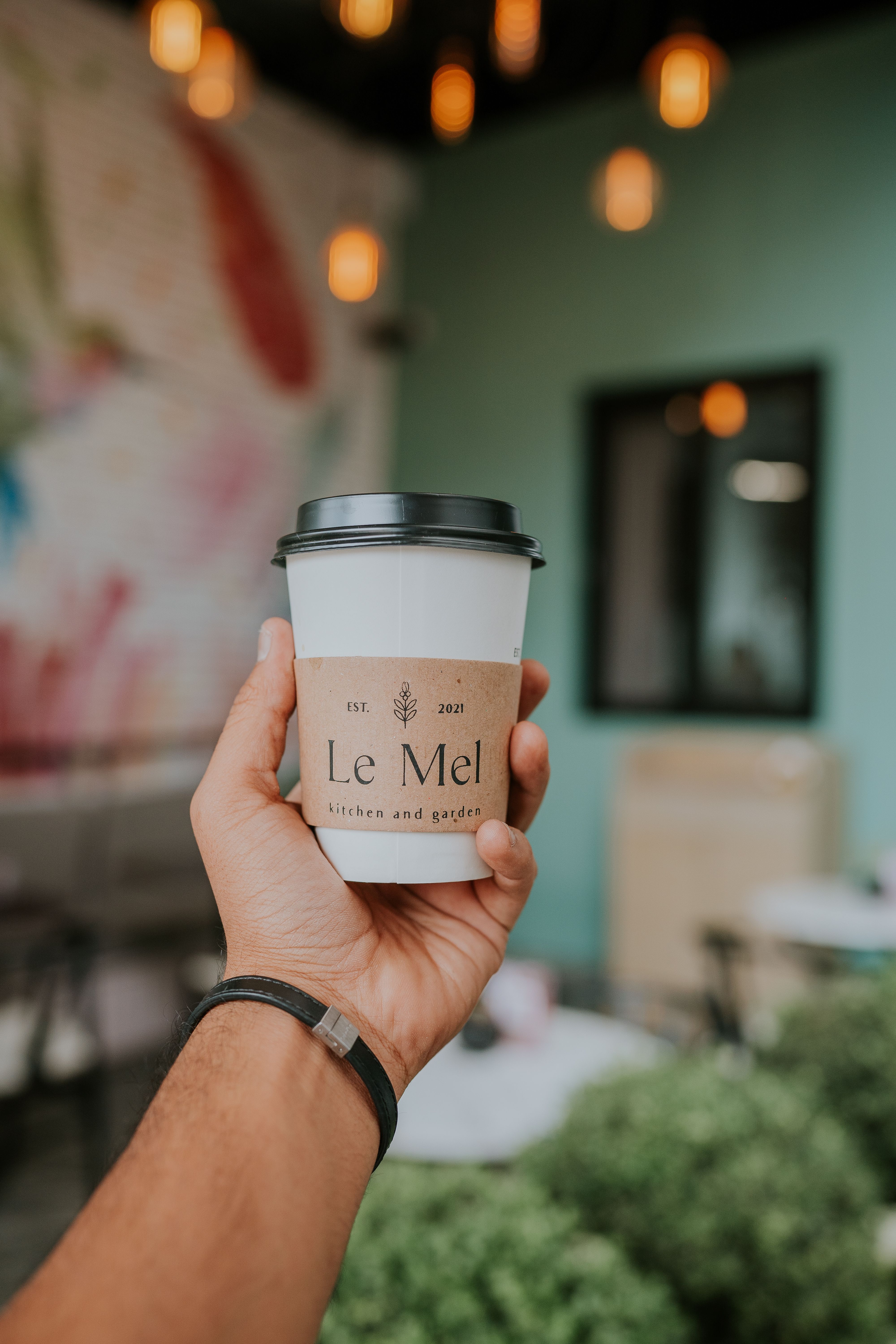 Fotomural Mano sosteniendo una taza de café en interiores con fondo artístico de café.