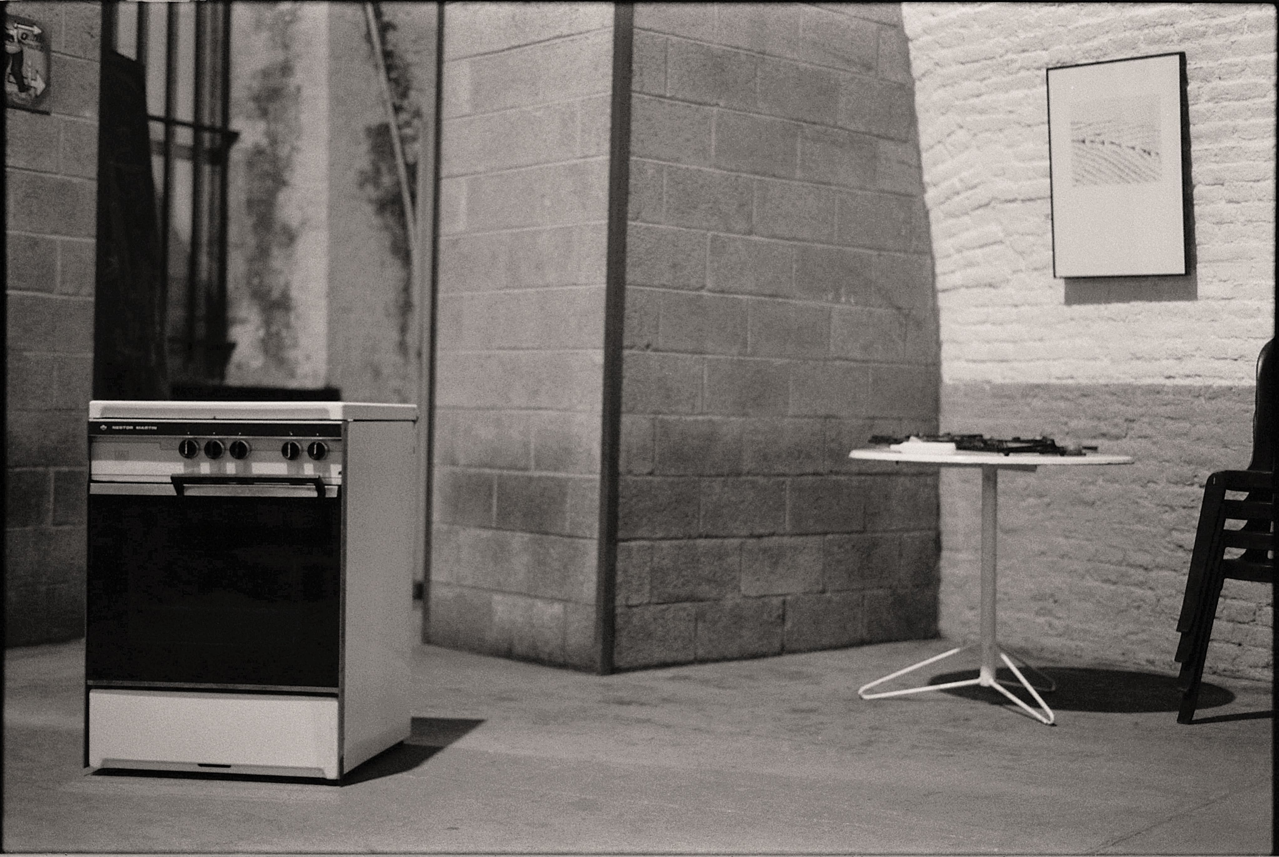 Imagem de uma cozinha industrial vazia, sugerindo limpeza ou preparação para uso, com destaque para o fogão a lenha e ambiente contemporâneo.