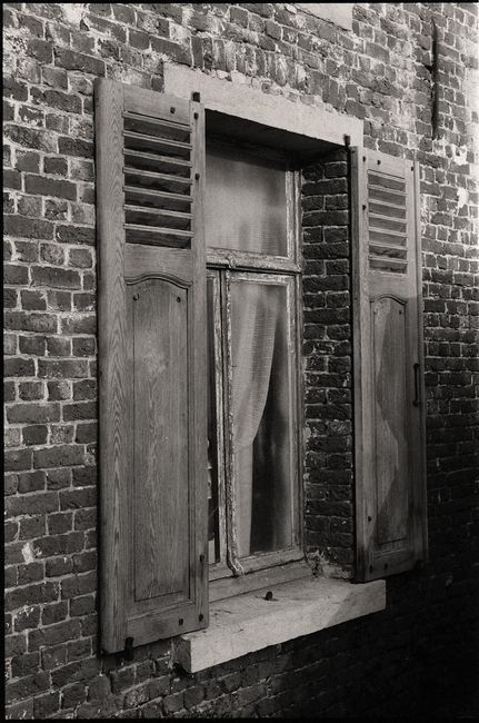 Black and white image of old brick wall with vintage wooden shutters.