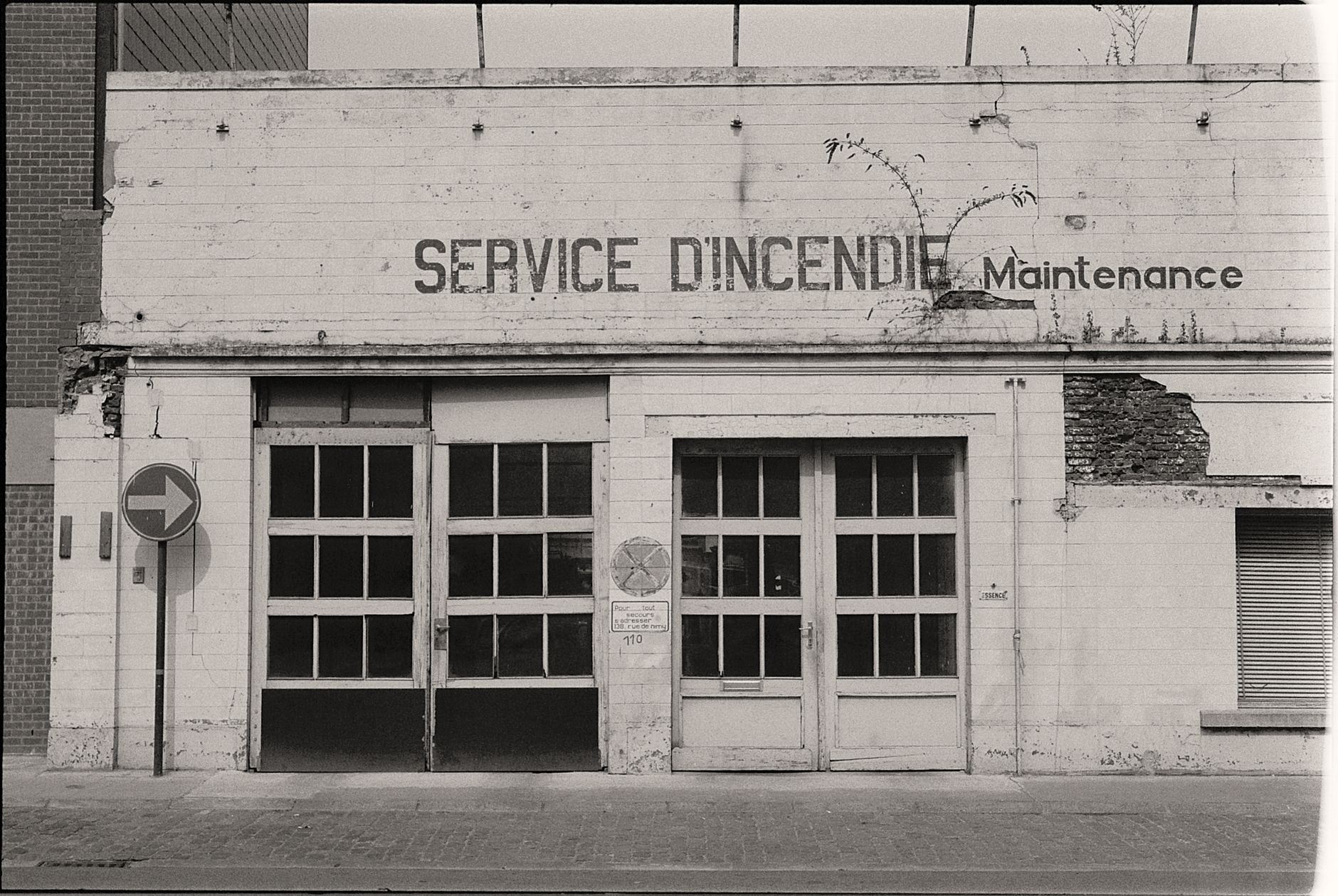 A black and white photo of an old fire service maintenance garage with signage.