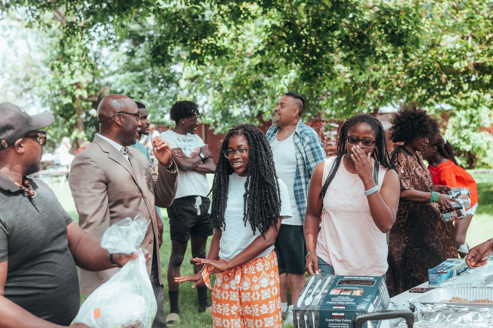 Diverse group of people talking and laughing together at an outdoor gathering in a park