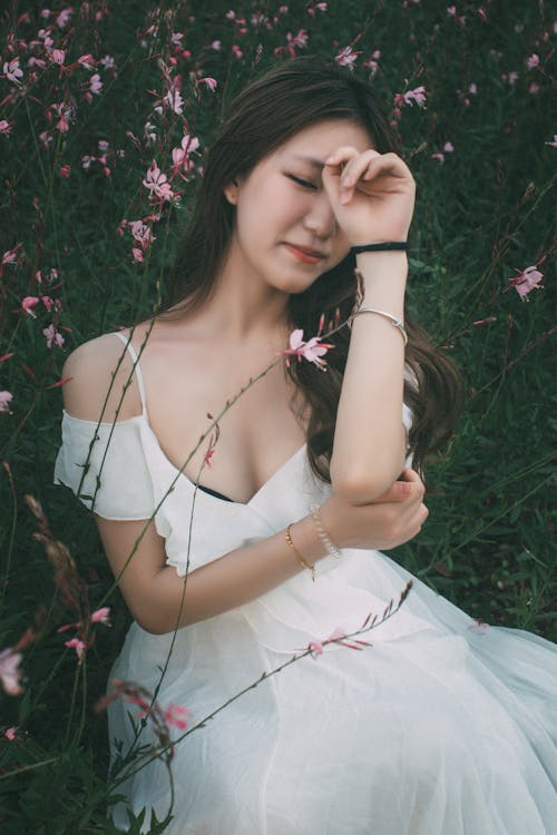 Woman in a White Dress Sitting in the Meadow 