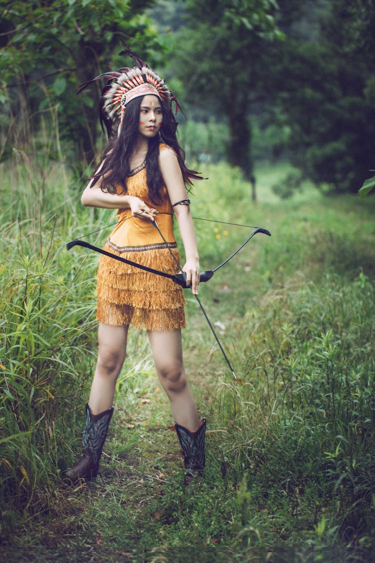 Woman In Native American Clothing Standing And Holding A Bow 