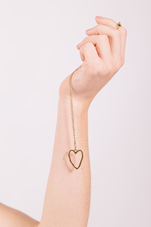 Free Close-up of a hand holding a heart-shaped pendant, symbolizing love. Stock Photo