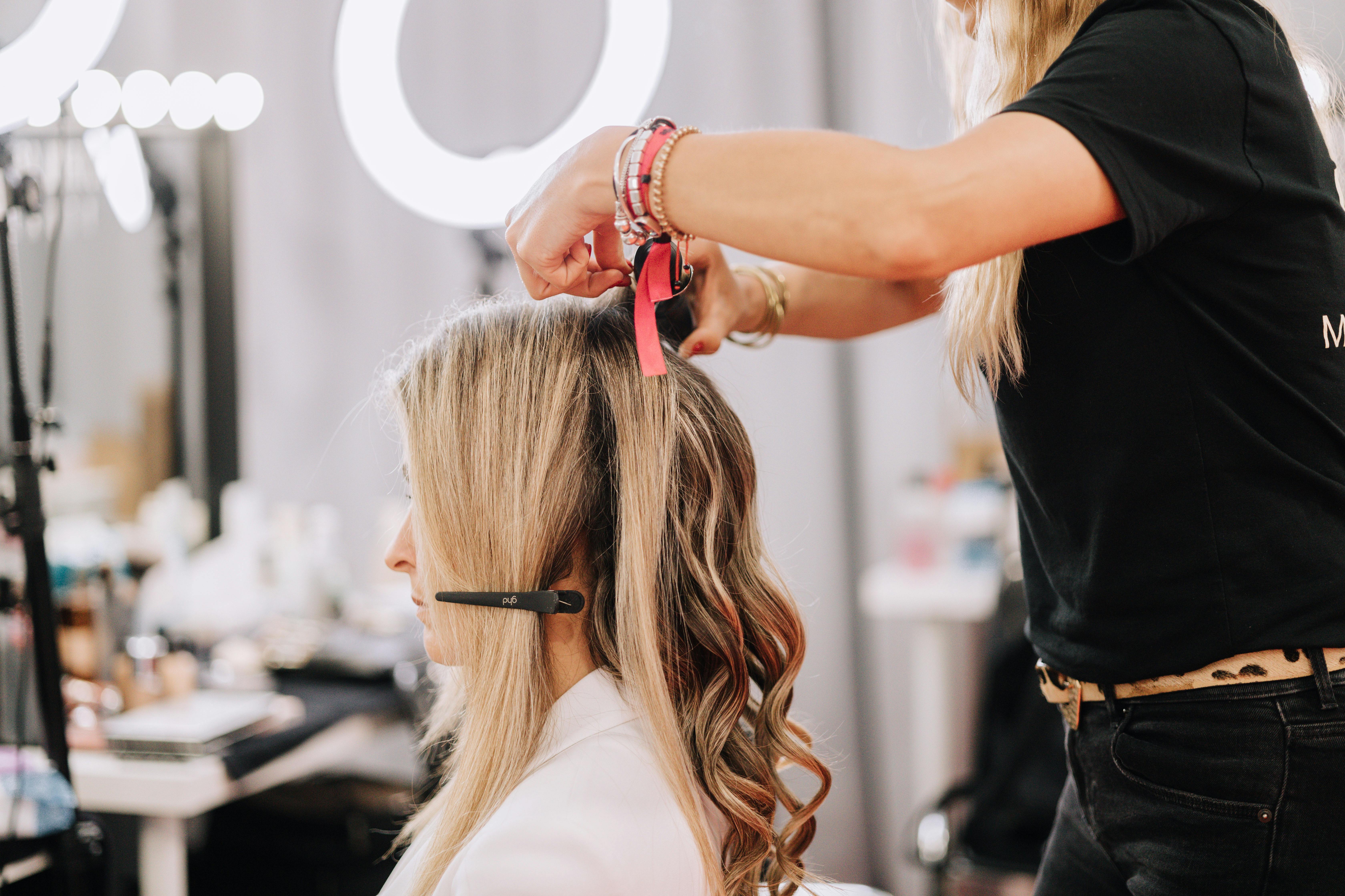 A stylist working on a blonde woman's hair during a studio session in Barcelona, Spain.