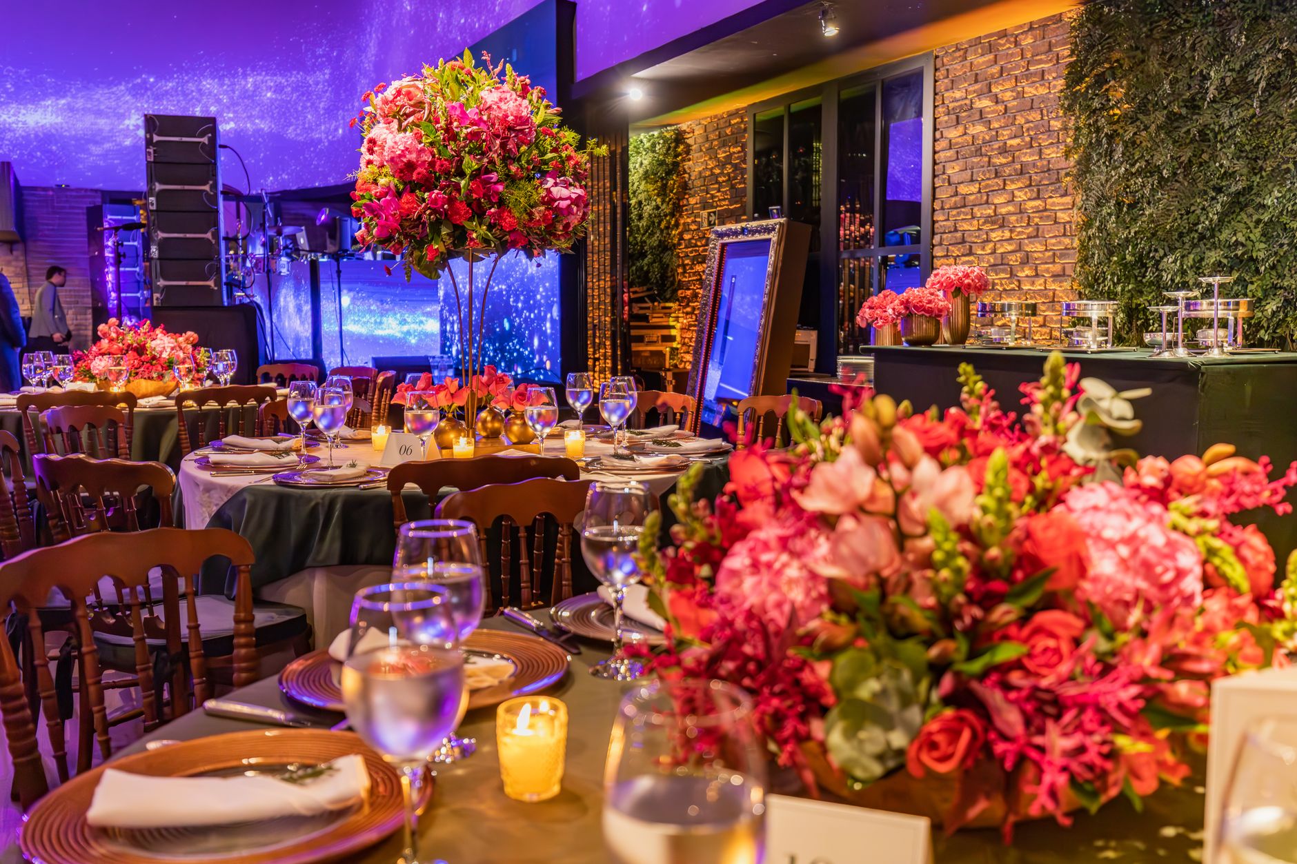 An indoor evening event setting with vibrant floral decorations and elegant table arrangements.