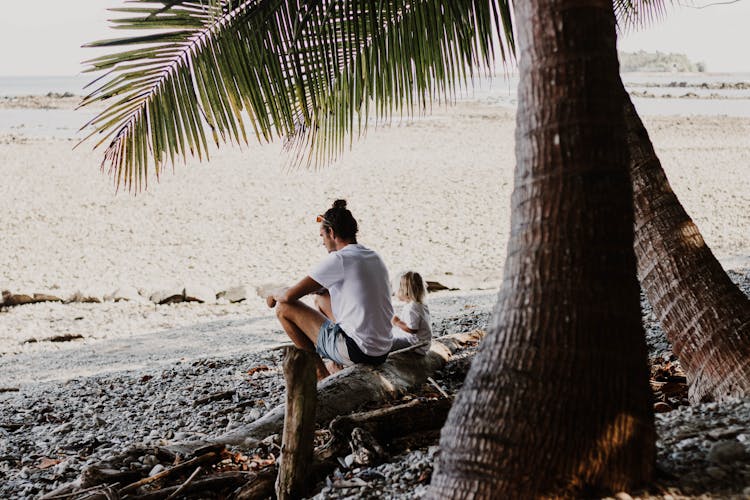 Man And Child Sitting On A Tropical Beach 