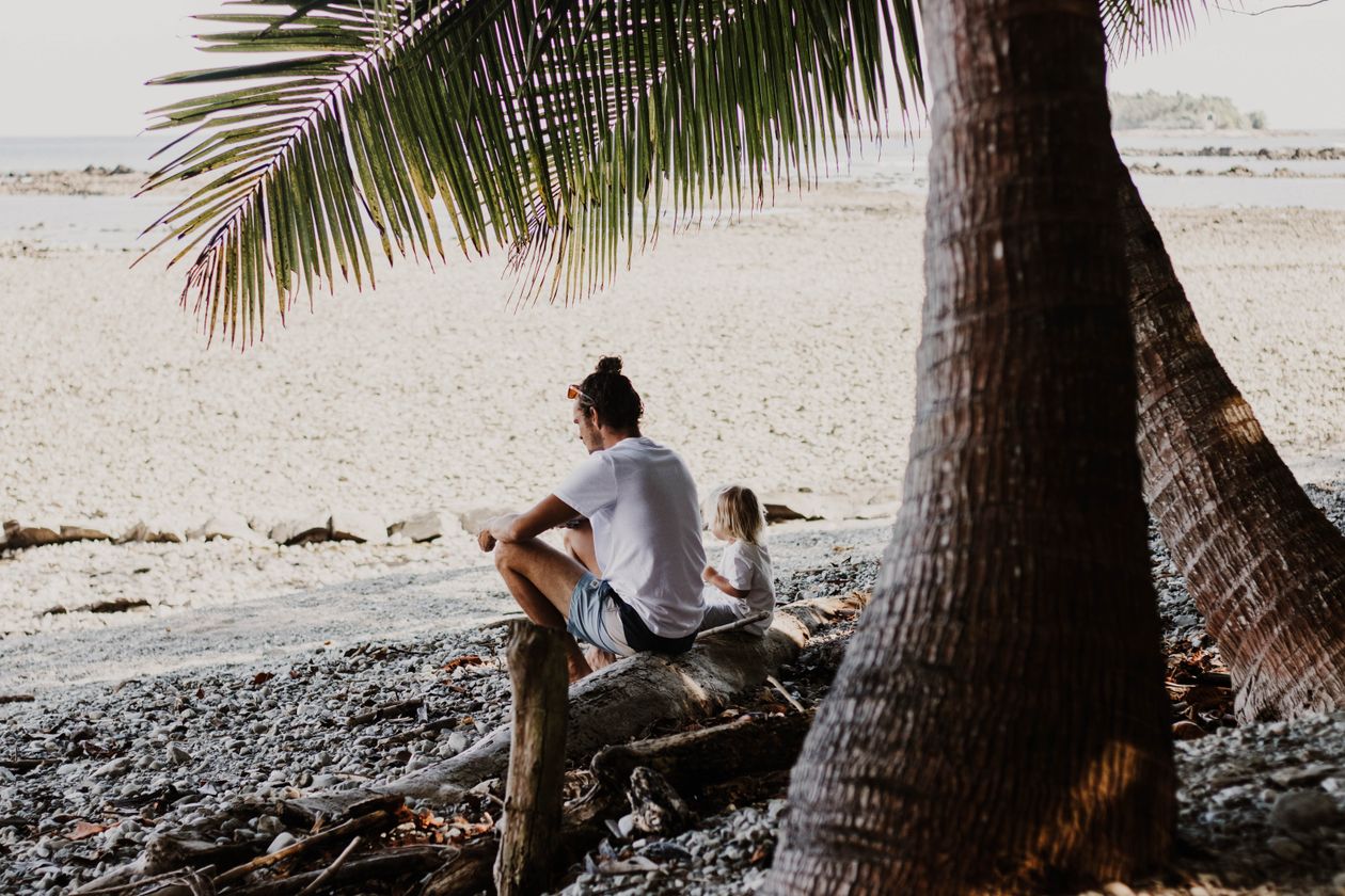Người cha và con nhỏ ngồi thư thái trên bãi biển nhiệt đới Costa Rica