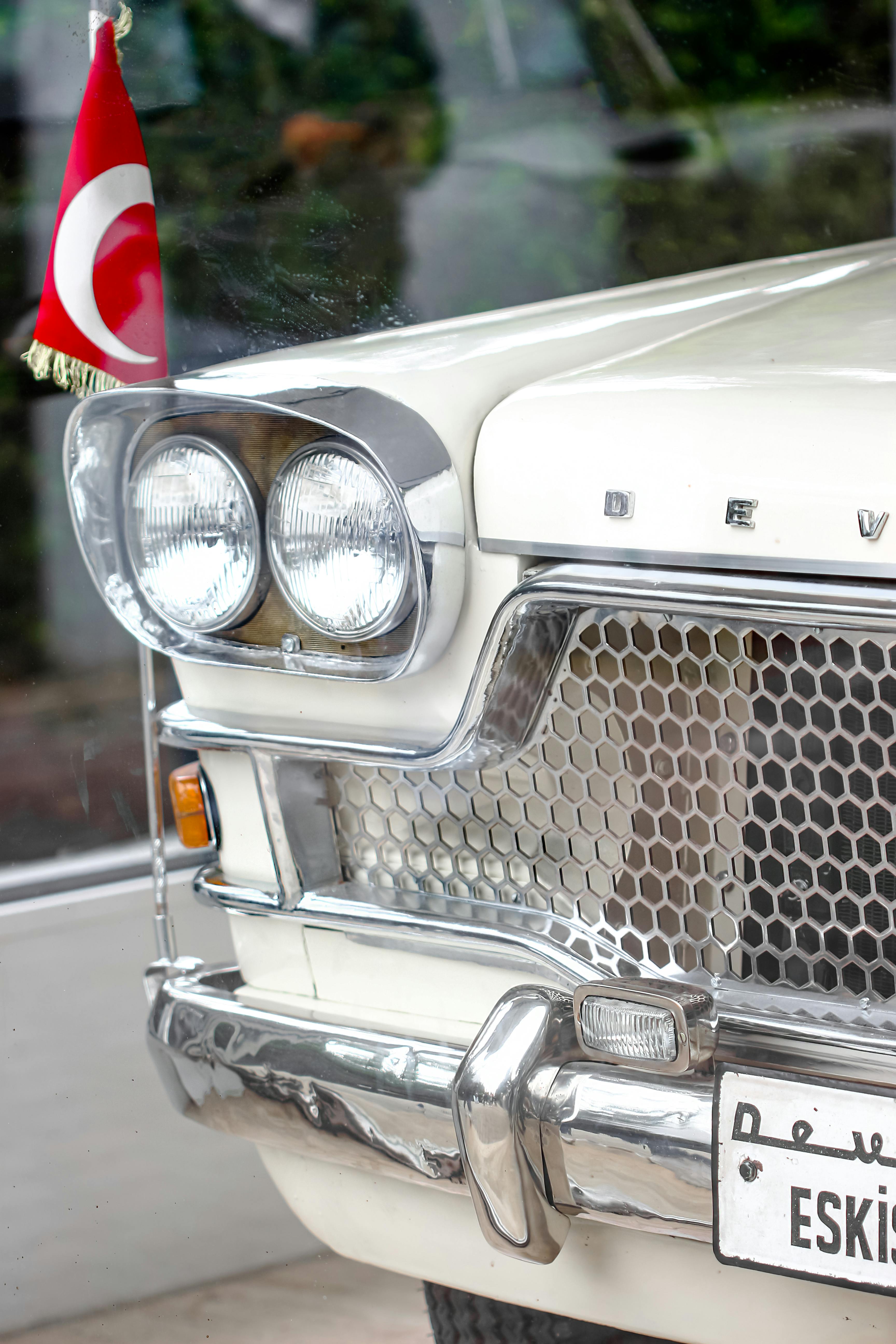 Close-up of a classic car's front with Turkish flag and shiny grille.