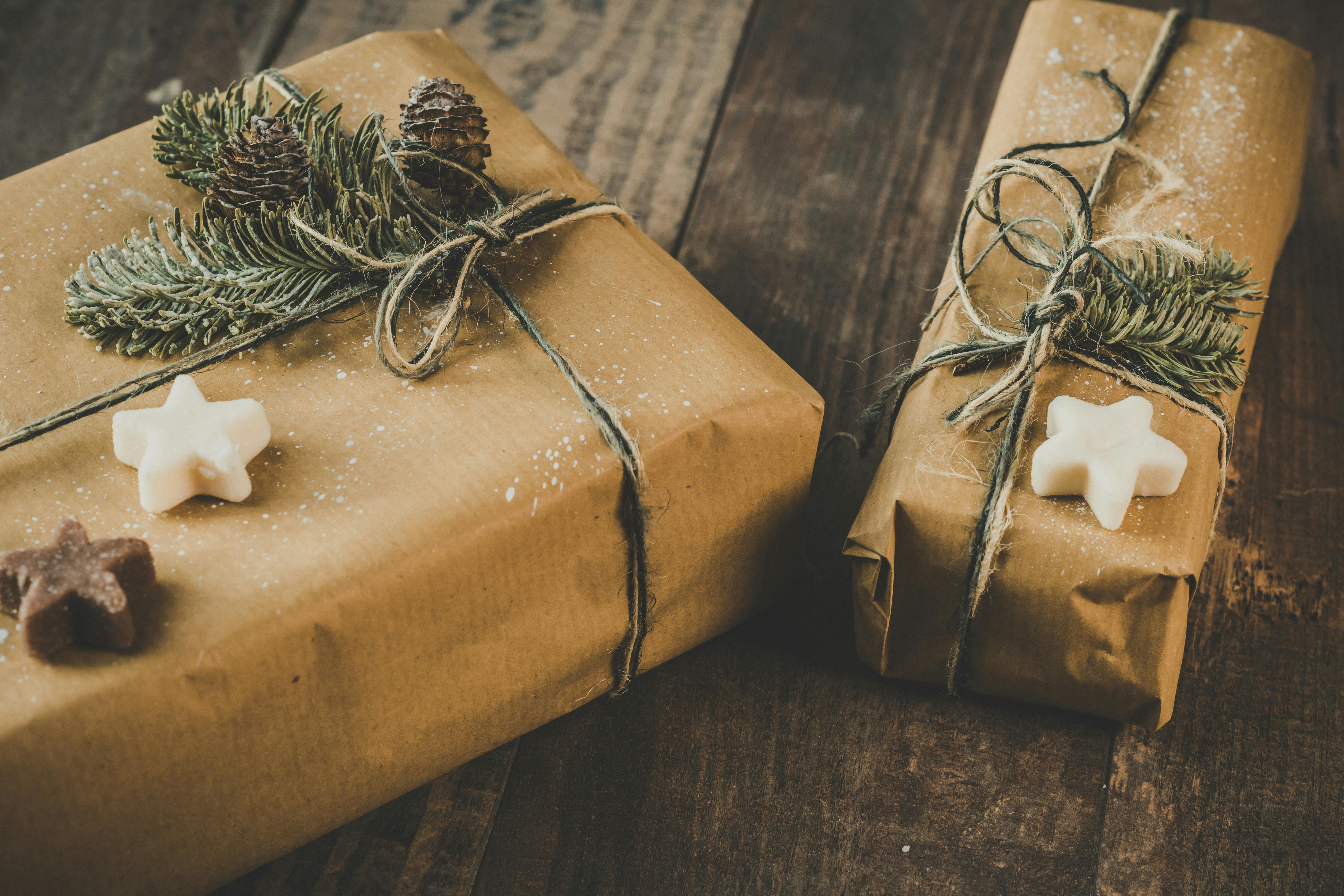 Free Two eco-friendly Christmas presents wrapped in brown kraft paper with pine decorations on a wooden table. Stock Photo