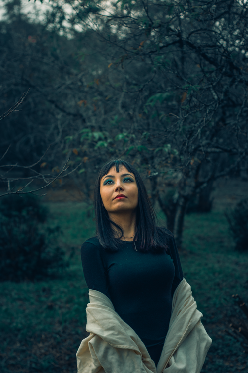 Free Woman posing gracefully outdoors surrounded by lush trees, capturing a serene and contemplative mood. Stock Photo