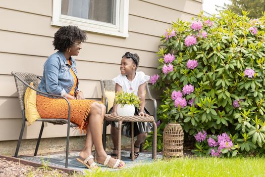 Mother and daughter smiling together in a blooming garden, enjoying leisure time.