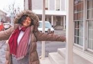 在冬天快乐的女人在城市街道上张开双臂微笑