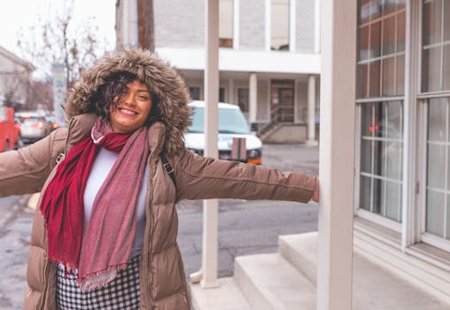 在冬天快乐的女人在城市街道上张开双臂微笑