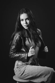 Stylish black and white portrait of a woman in leather jacket posing confidently.