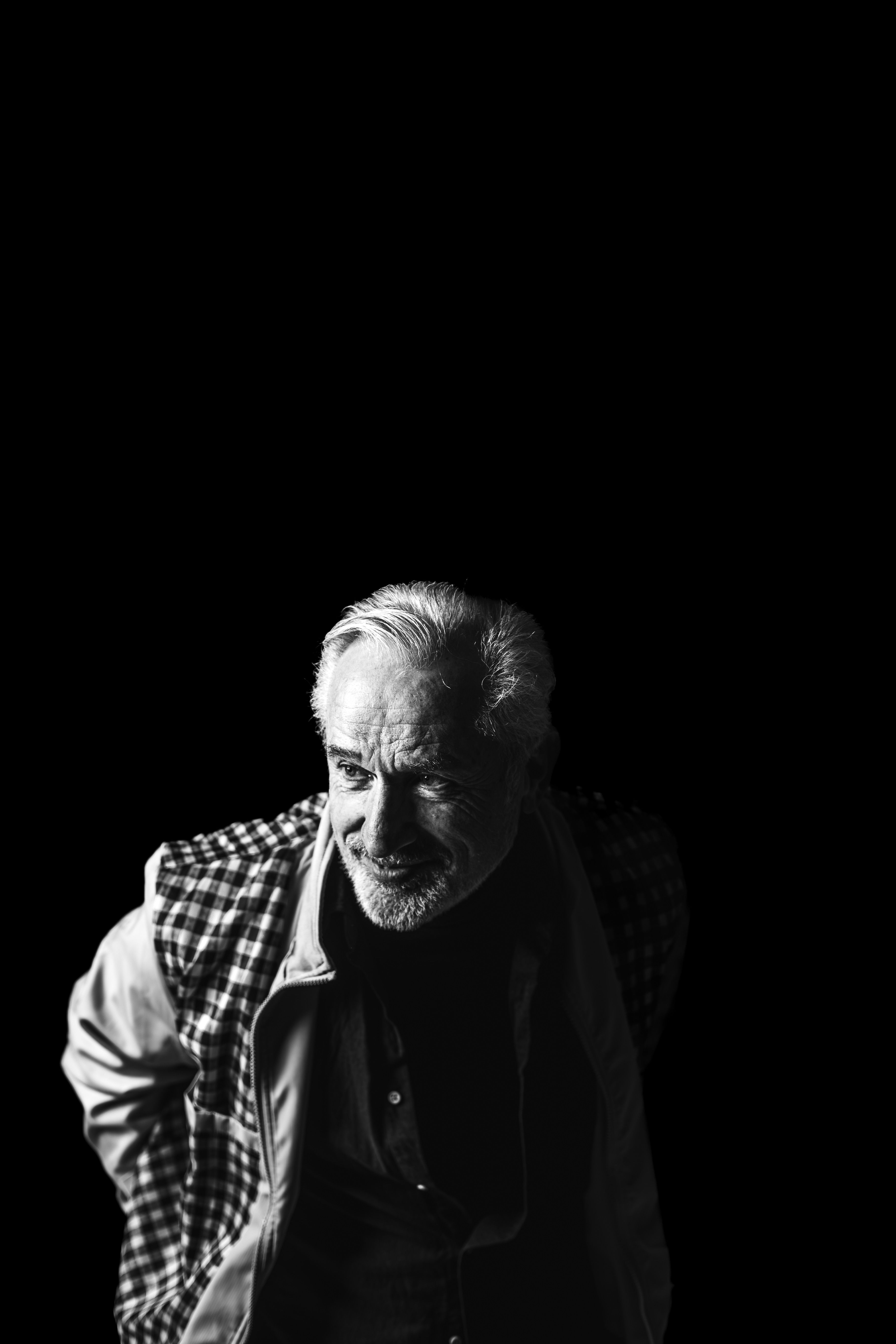 Captivating black and white portrait of a distinguished senior man against a black background.
