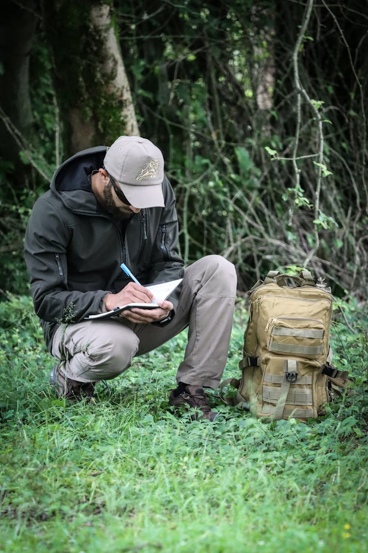 Man Writing In Notebook In Forest