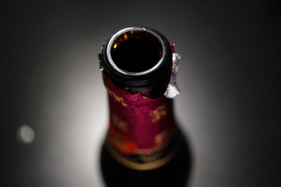 A half-finished bottle of red wine with its cork pushed back in, sitting on a kitchen counter