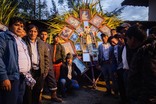 Men gather around a colorful religious display in a nighttime cultural celebration outdoors.