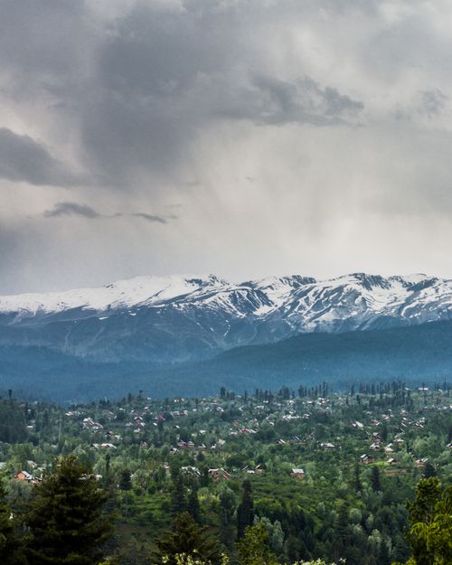 Free A breathtaking aerial photo capturing Srinagar's lush landscape with snowcapped mountains under overcast skies. Stock Photo