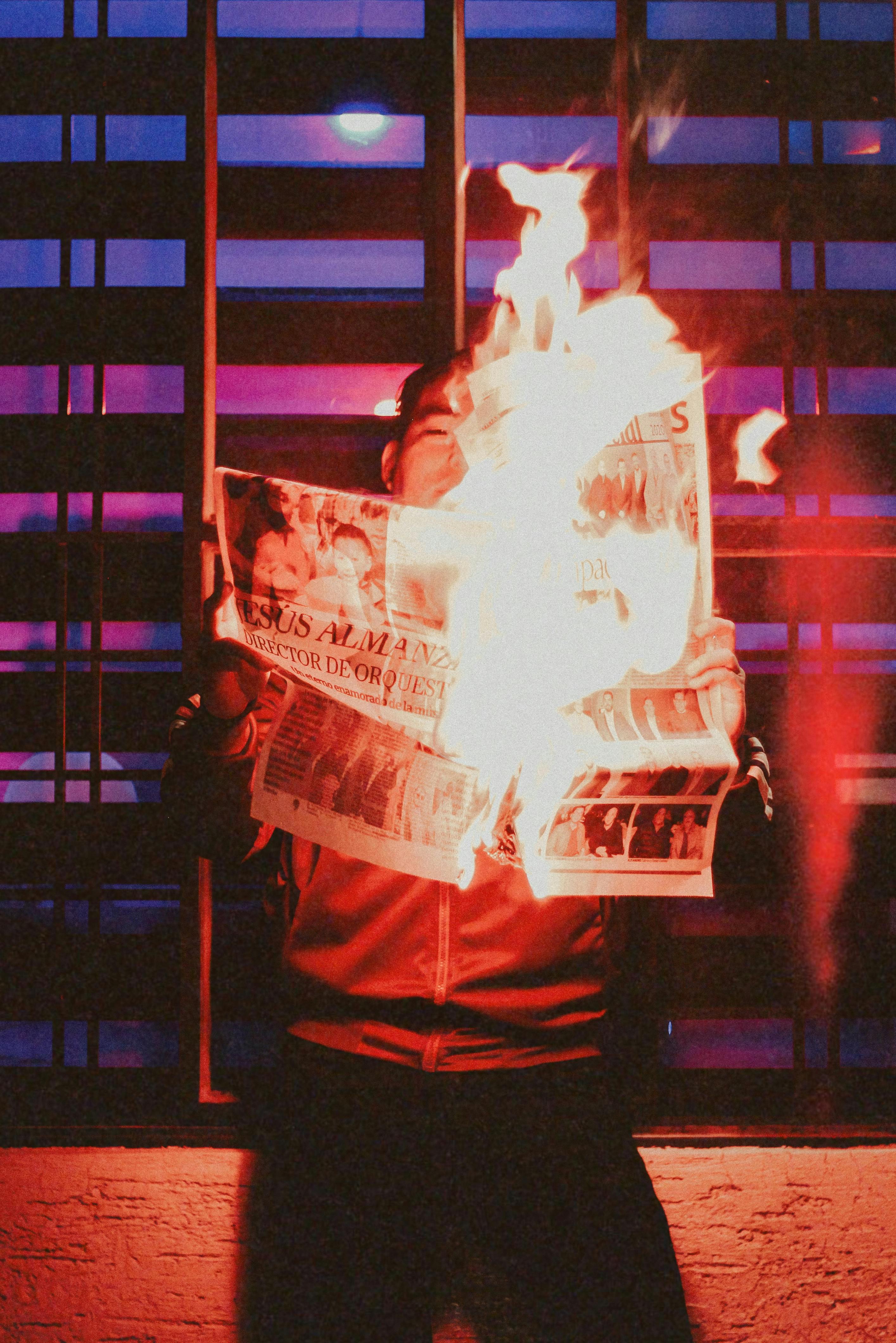 Dramatic scene of a man with newspaper on fire, creating an artistic night composition.