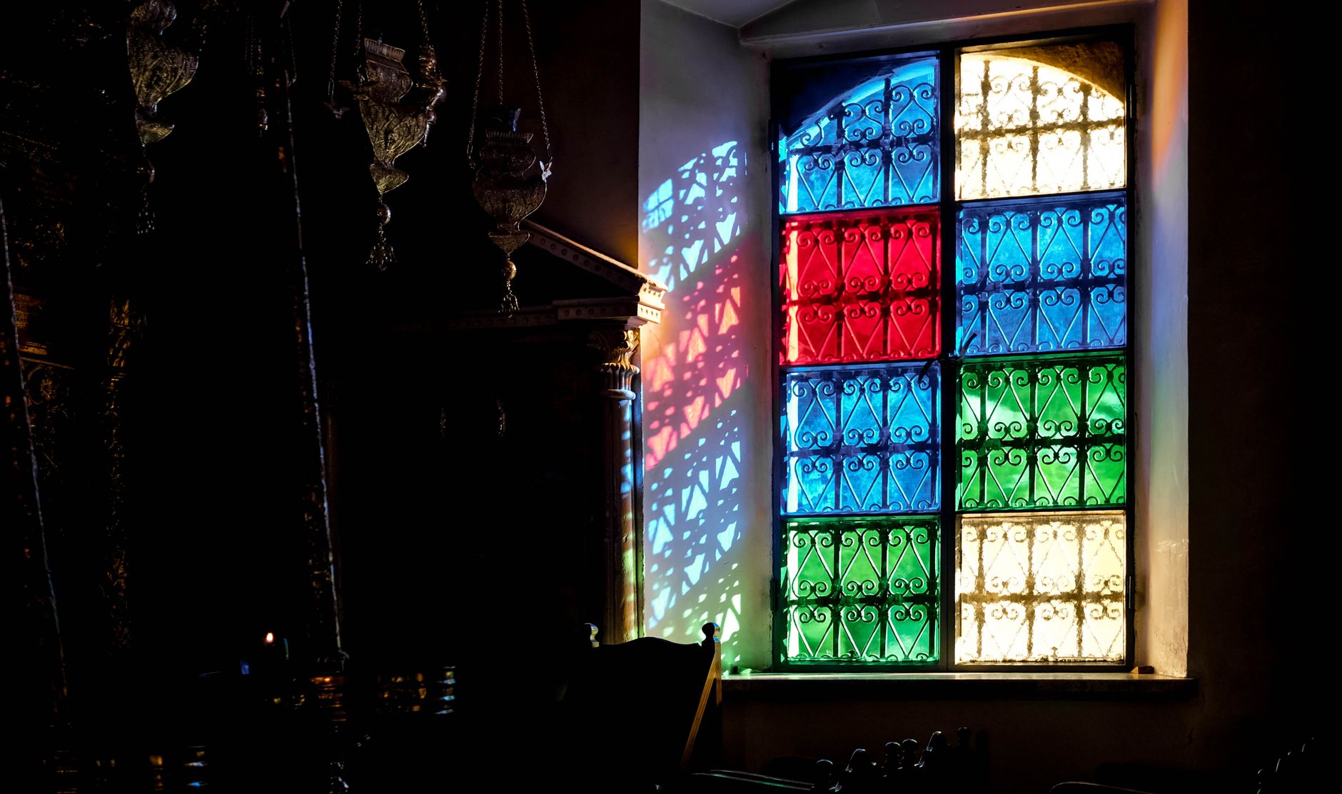 Coloured light falling across a quiet room from a stained glass window