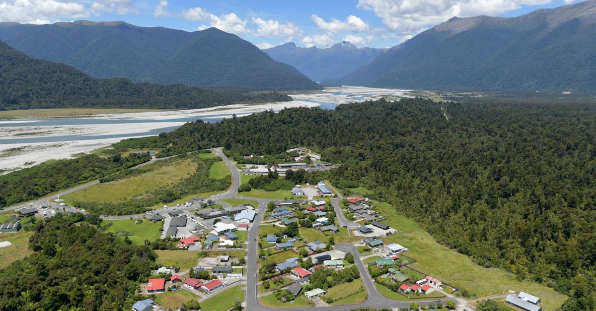 Scenic aerial view of Haast village with lush forests and mountains in the background.
