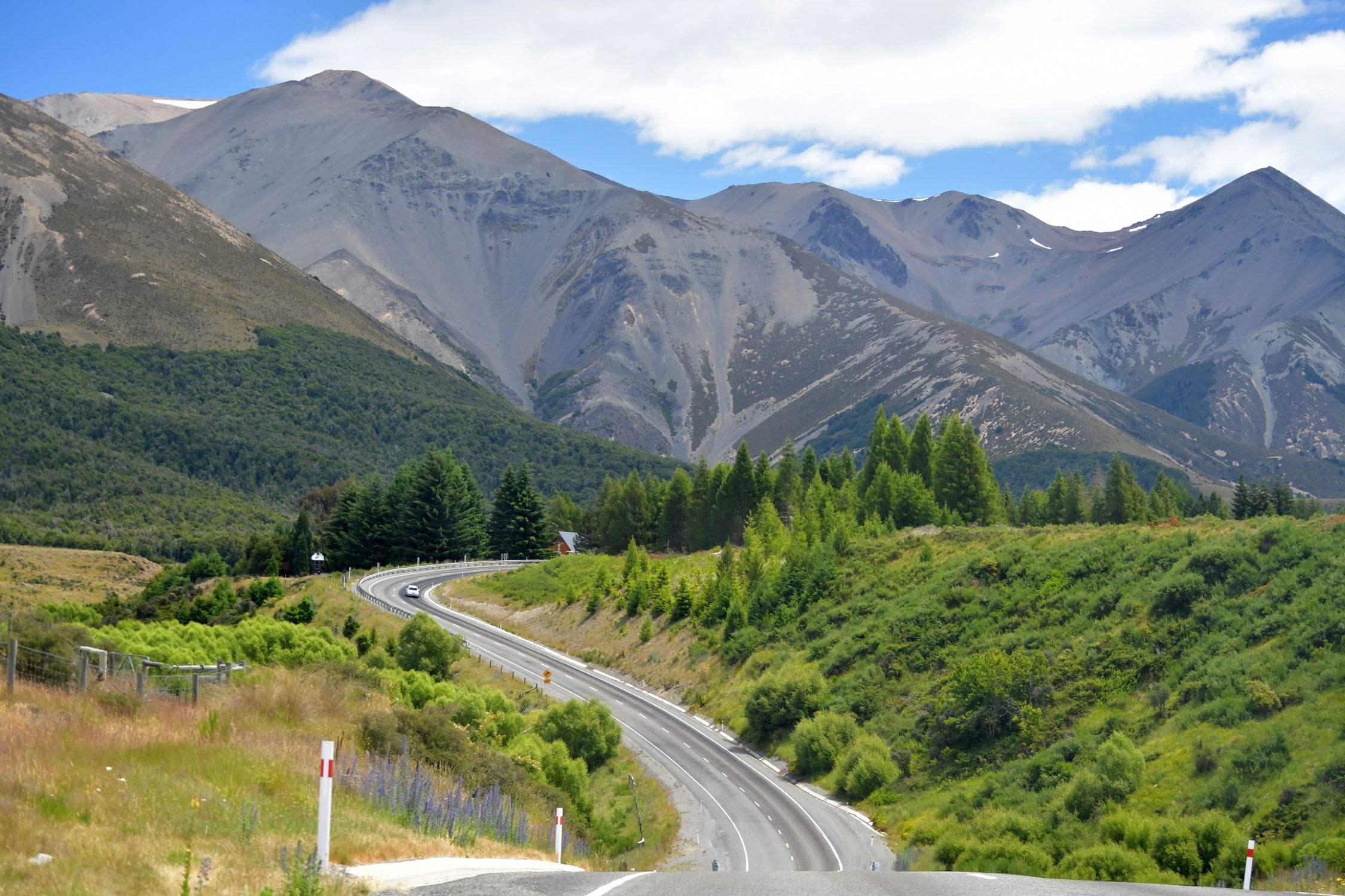 Breathtaking view of a winding road through the mountainous landscape of Castle Hill, New Zealand.