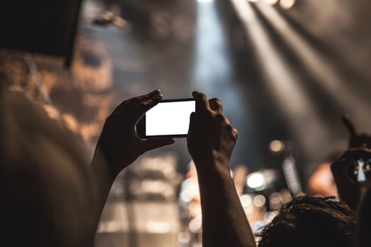A vibrant concert scene featuring a smartphone capturing the live music experience.