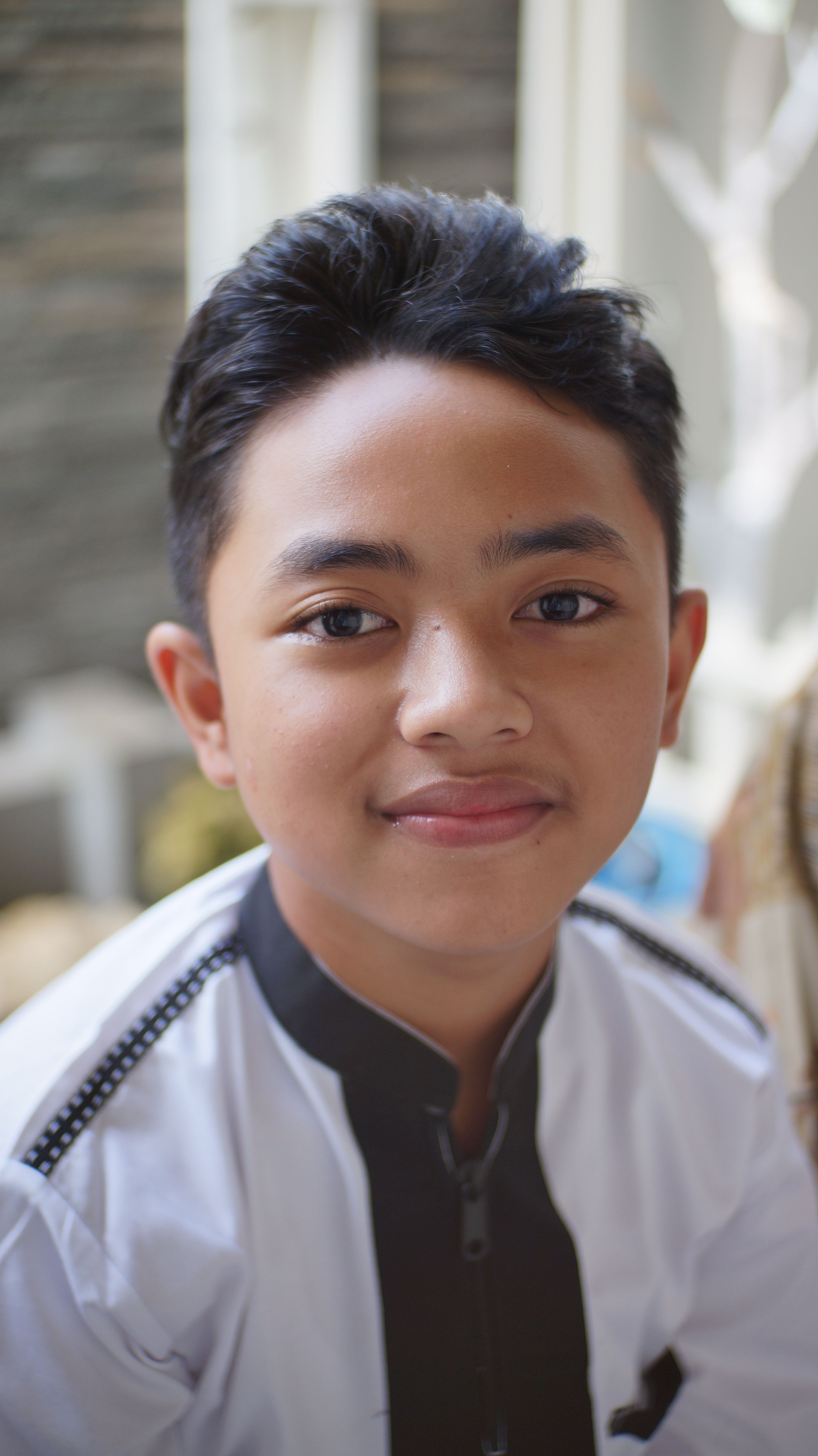 Close-up portrait of a smiling boy in traditional clothing, indoors.