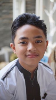 Close-up portrait of a smiling boy in traditional clothing, indoors. - Fotografer Sidoarjo