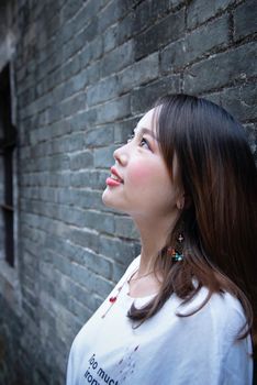 Close-up of a young woman looking up with a smile against a brick wall background.