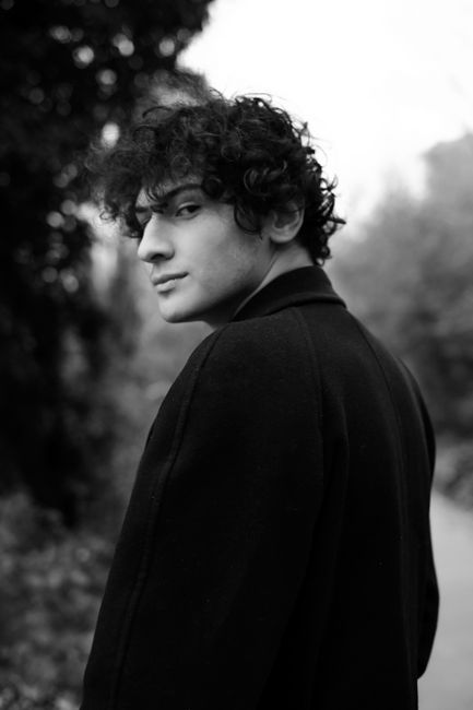 Black and white portrait of a young man with curly hair outdoors in Türkiye.