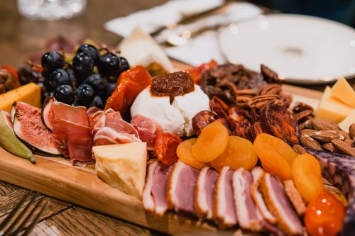 Free Delicious gourmet charcuterie board featuring an assortment of meats, cheeses, nuts, and fruits. Stock Photo