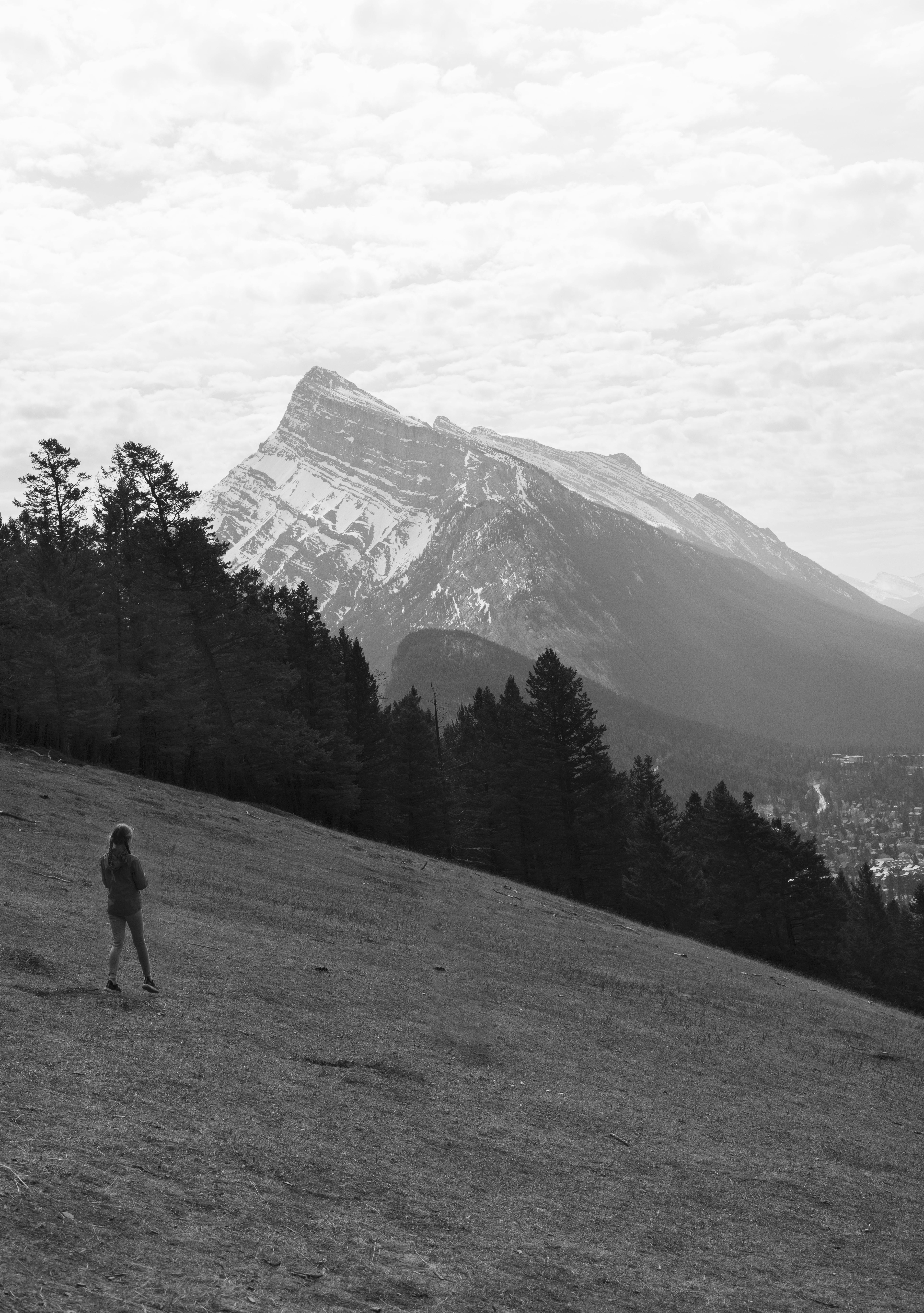 A woman hikes in Banff, AB, Canada with a stunning view of Mount Rundle in black and white.