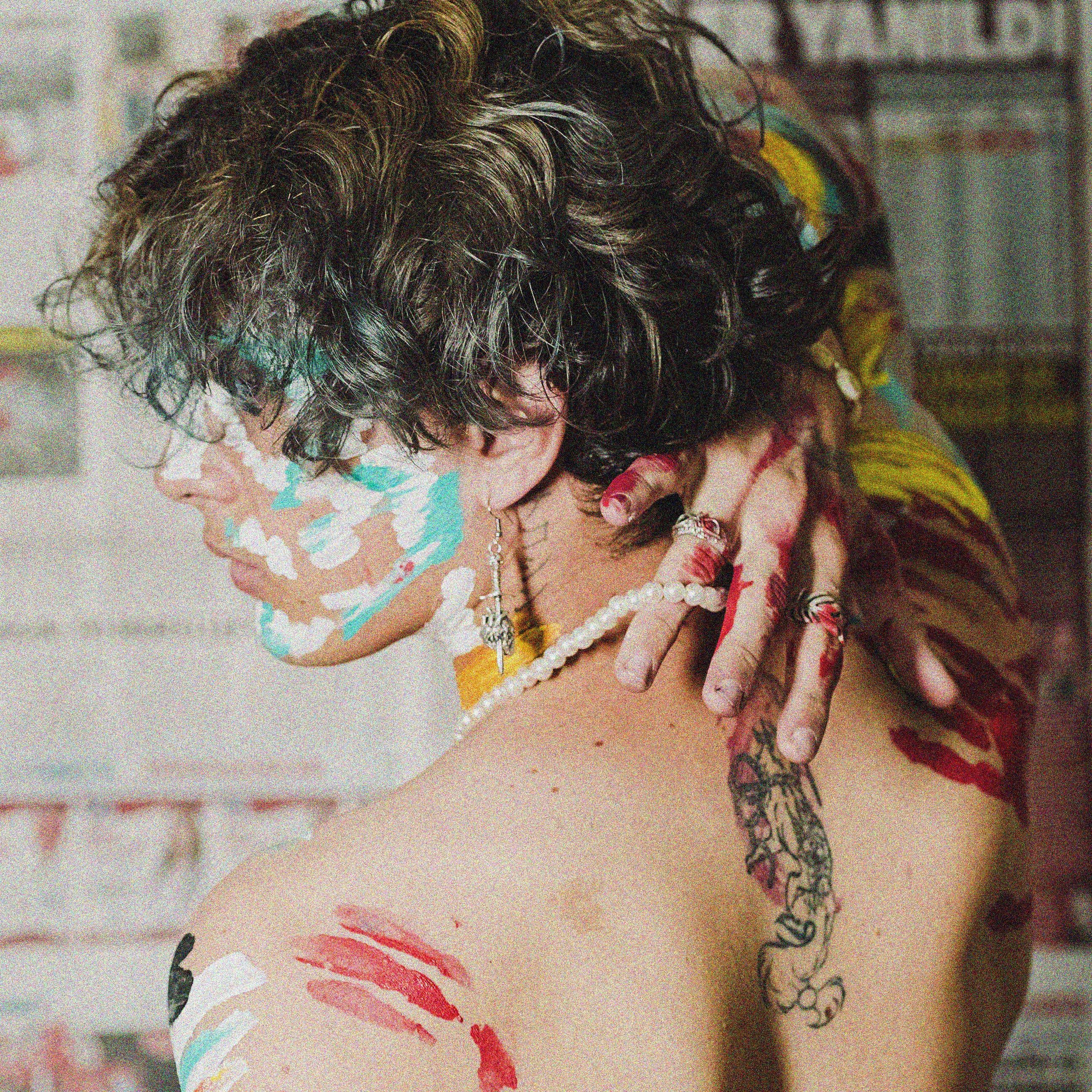Man with paint-covered skin in artistic expression, embracing creativity.