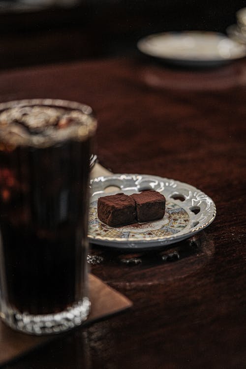 A Glass with a Drink and Chocolate on the Table 