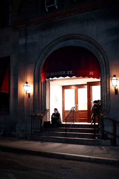 Woman Sitting on Steps in Entrance to Building