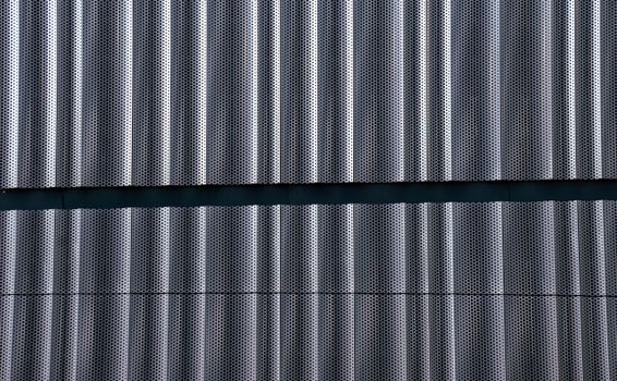 Close-up of perforated metal panels creating an abstract geometric pattern on a wall.