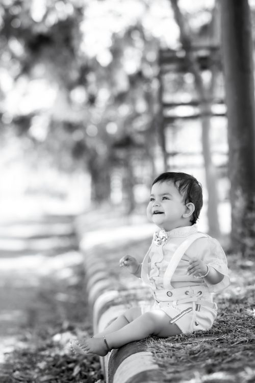 Free Adorable baby sitting and smiling outdoors in a black and white setting, showcasing innocence and joy. Stock Photo