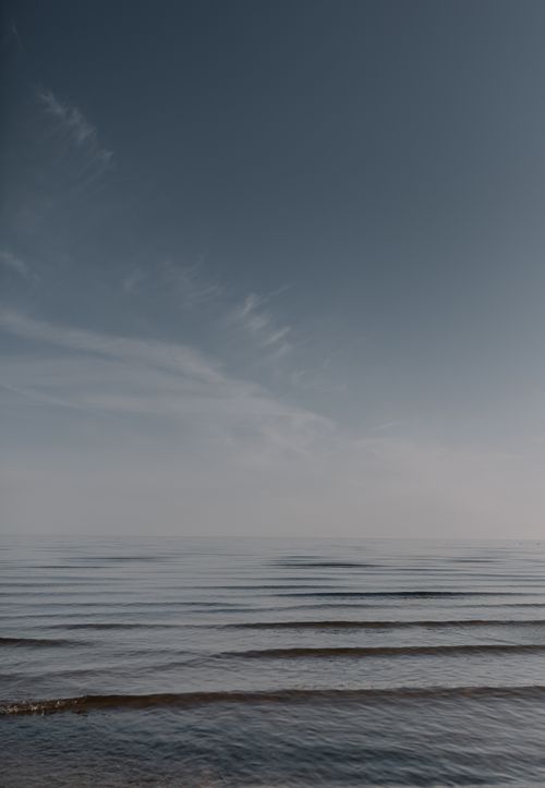 Free A calming view of an expansive ocean horizon under a clear blue sky with rippling waves. Stock Photo