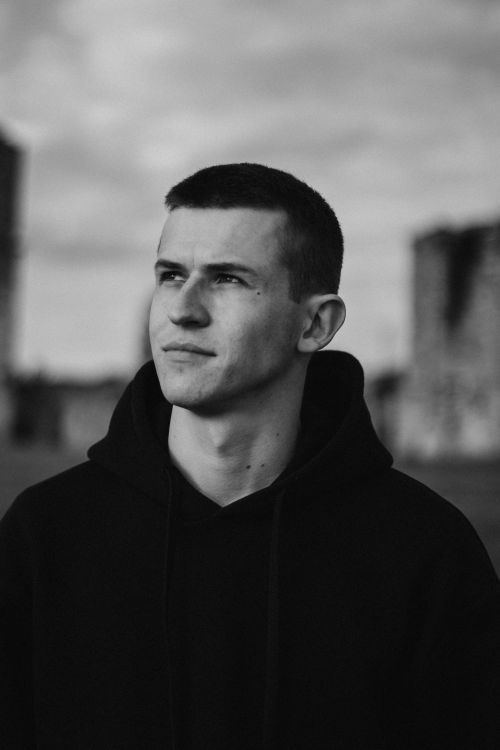 Free Striking black and white portrait of a man wearing a hoodie, looking contemplative outdoors. Stock Photo