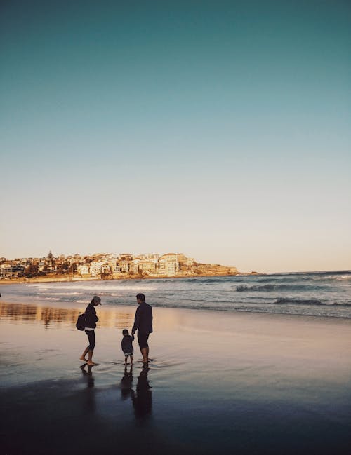 Free Man and Woman Walking With Boy in Seashore Stock Photo