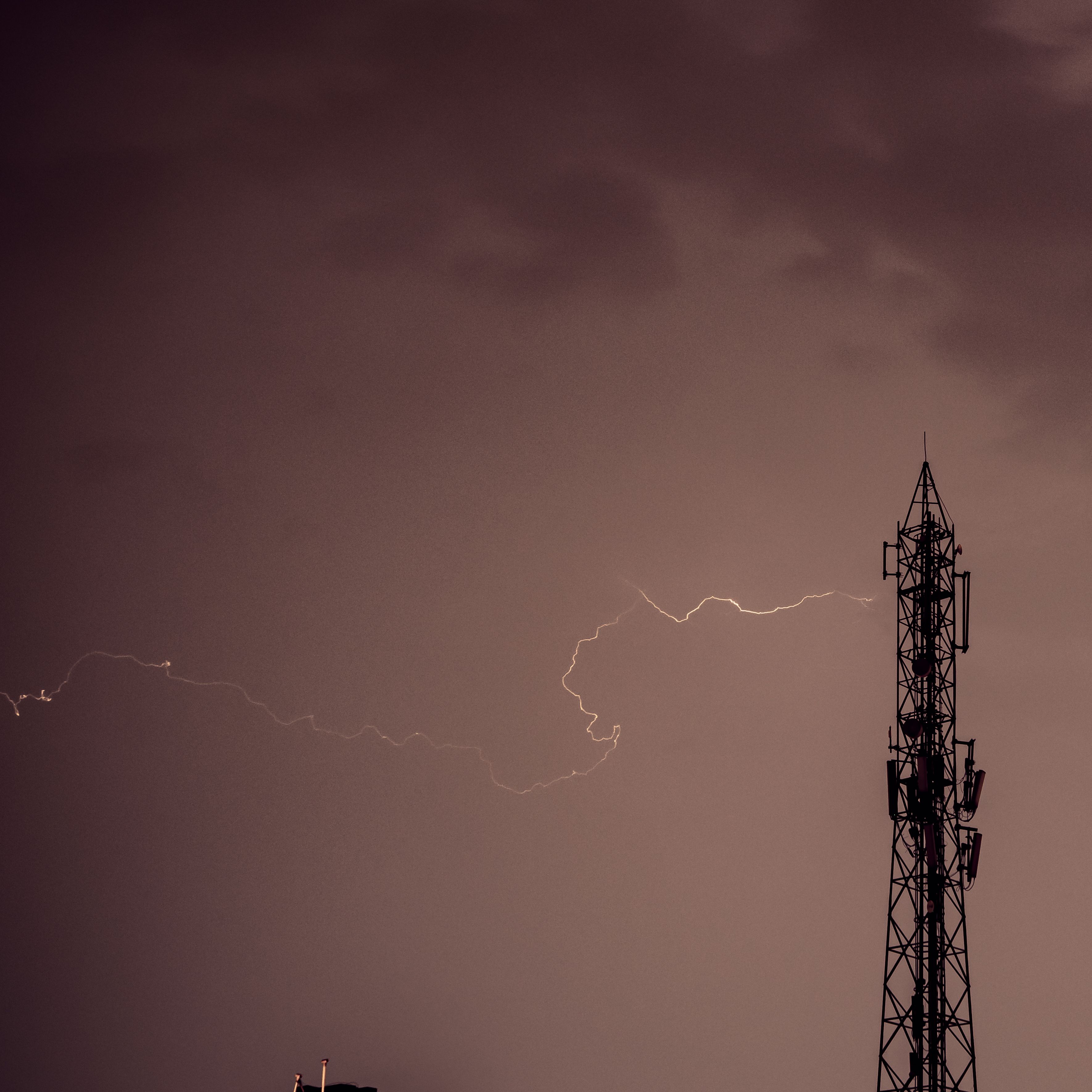 A dramatic view of lightning striking near a tower against a stormy sky.