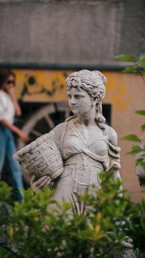 Free A detailed stone statue of a woman with a basket in a city park. Stock Photo
