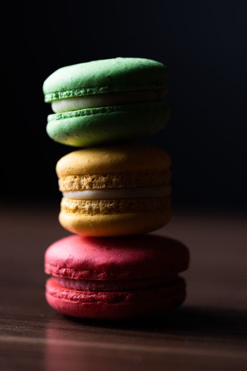 Free A stack of green, yellow, and red macarons on a wooden surface, perfect for dessert lovers. Stock Photo